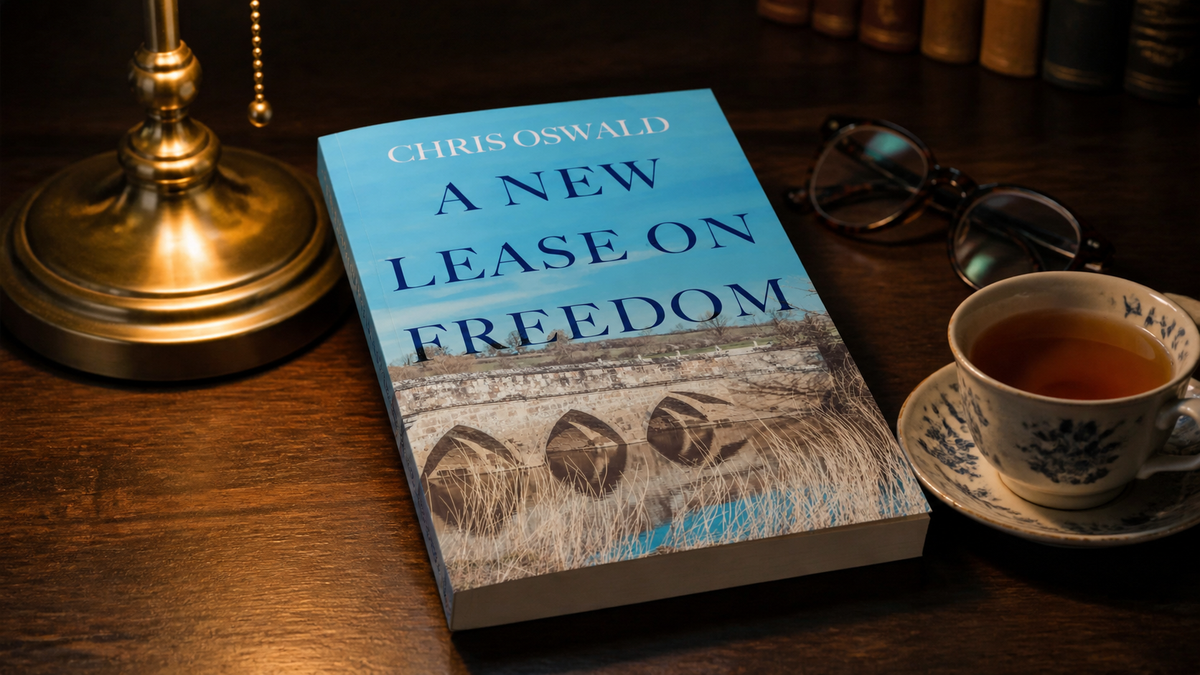 A New Lease on Freedom paperback on a desk beside a brass lamp and a cup of tea